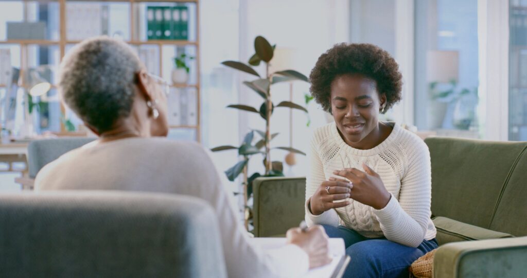 Young Woman in Counseling Session With Therapist on Cozy Office Couch Discussing Mental Health